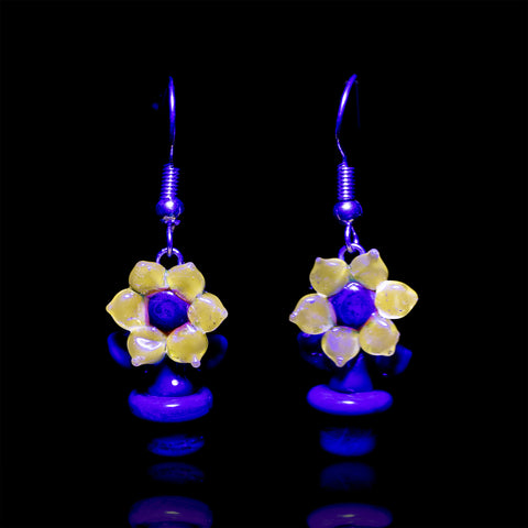 Two sunflower style dangle earrings shined under UV light featuring the yellow glow of the sunflowers' petals.