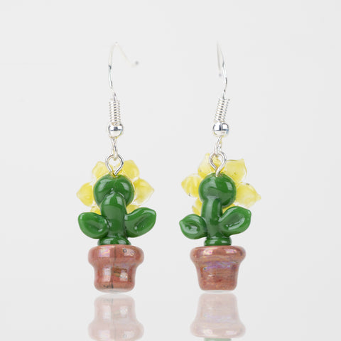 The backside of the sunflower themed dangle earrings. Each piece features a green stem and leafs, with yellow petals and a brown pot.