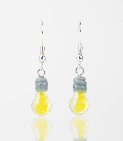 A set of two light bulb shaped dangle earrings hanging side by side. The Light bulb is yellow with a clear shell and grey threads. Attached to the threads is a sterling silver earring backing.