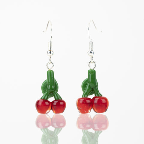 Two cherry themed glass earrings facing away from the camera, showcasing the rear of the earring. Each earring has two cherry red cherries attached to a green leaf. Above each leaf is a sterling silver dangle backing. 