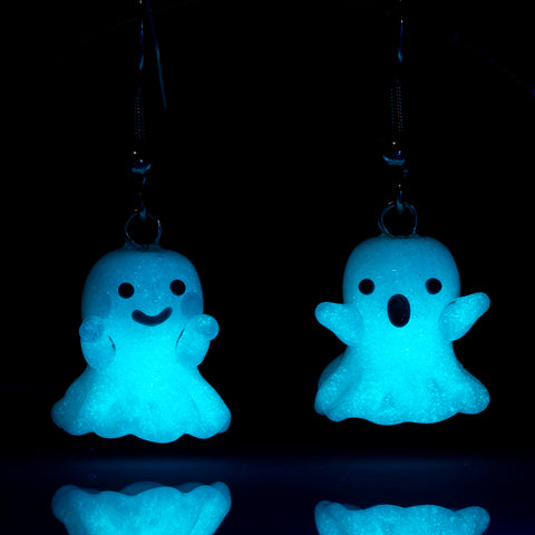 A pair of two ghost shaped earring under dark-light glowing in the dark