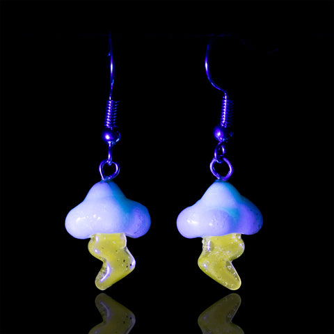 A pair of lightning cloud themed dangle earrings shined under UV light with the cloud and lightning bolt glowing.
