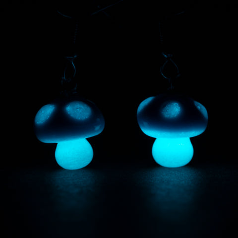 Pair of glowing blue mushroom earrings under UV light