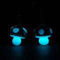 A pair of mushroom earrings glowing in the dark