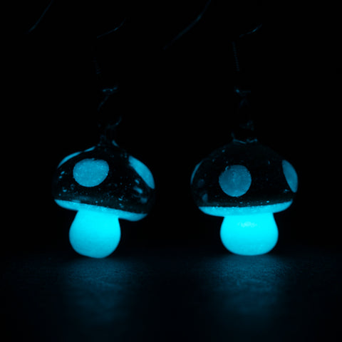 A pair of mushroom earrings glowing in the dark
