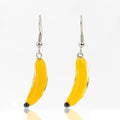 Pair of yellow glass banana earrings on white background
