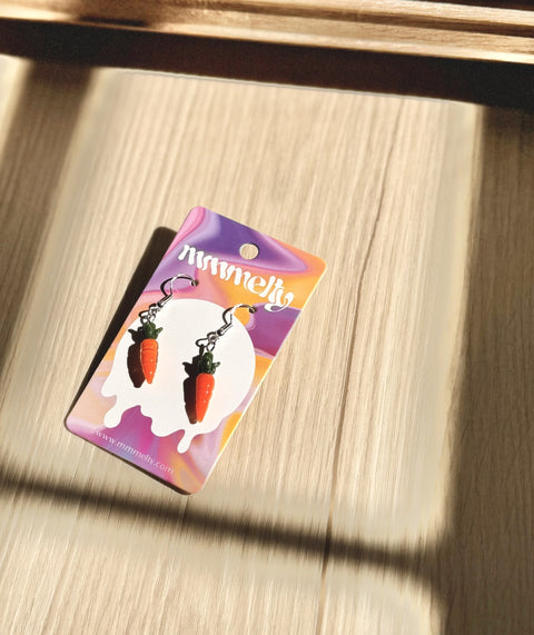 Pair of orange and green glass carrot earrings on white background