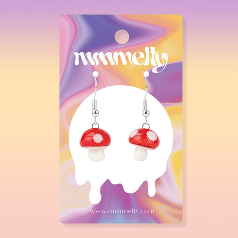 Pair of red and white glass mushroom earrings on white background