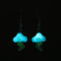 Two lightning cloud earrings under low light showcasing the glow in the dark features of the cloud. Below the cloud are the translucent lightning bolts.  
